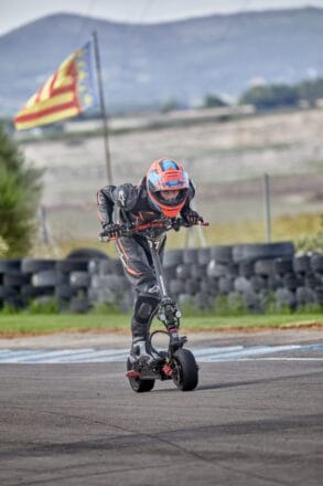 Piloto en scooter eléctrico en pista de carreras.