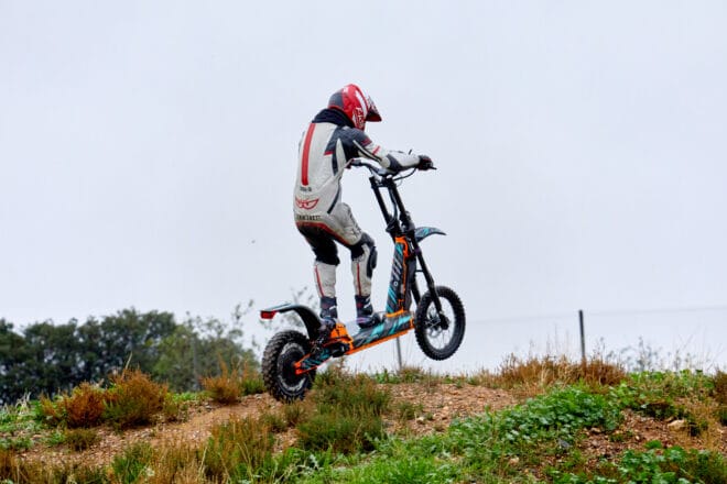 Persona saltando en scooter eléctrico sobre colina.